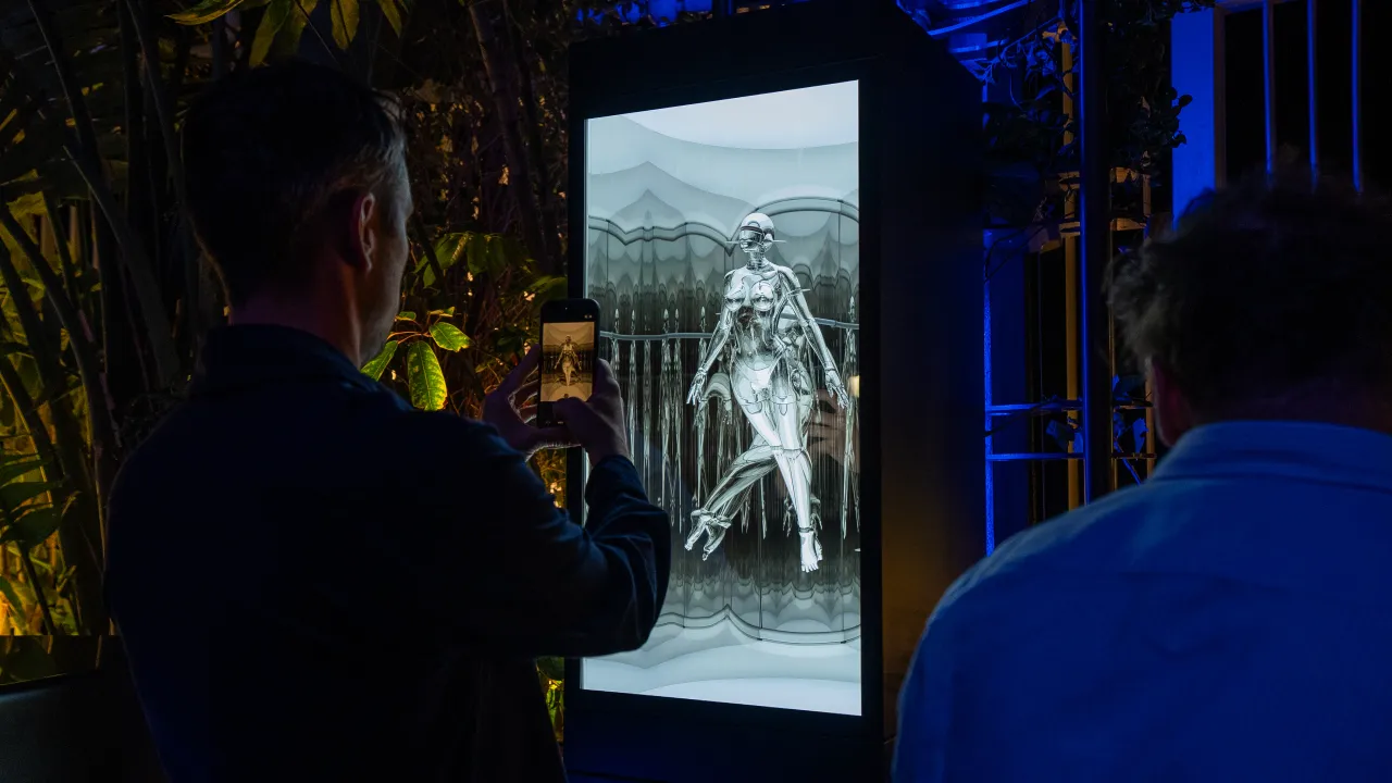 A clubber takes a picture of Sexy Robot artwork by Japanese Illustrator Hajime Sorayama